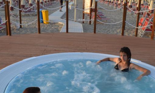 Two people relaxing in a hot tub on the beach.