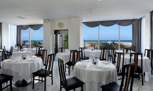 Ristorante elegante con vista mare, tavoli apparecchiati.